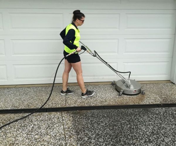 person pressure washing pebblecrete driveway cleaning with heavy duty pressure washing equipment